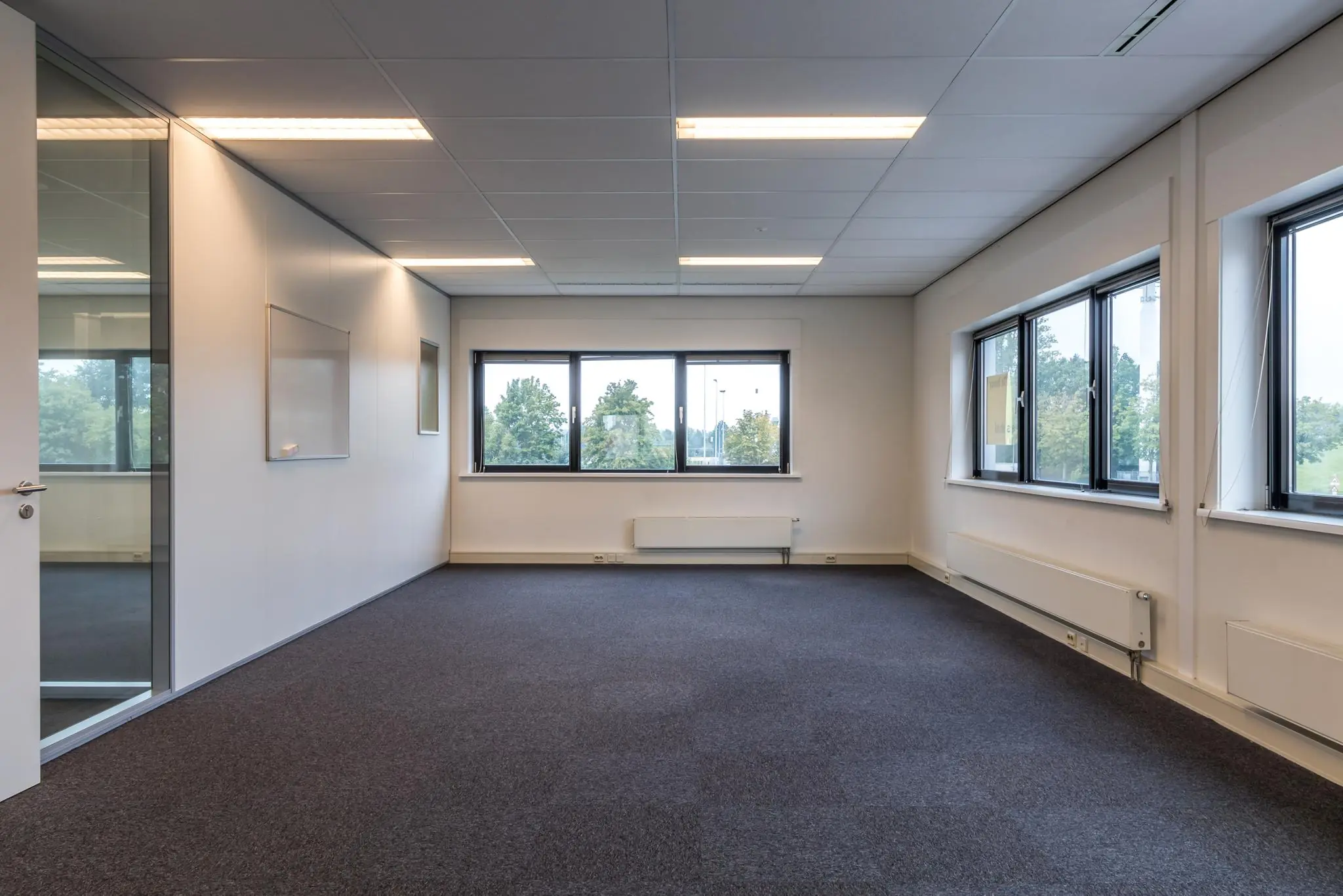 Lichte, lege kantoorruimte aan de Lage Biezenweg met grote ramen en systeemplafond.